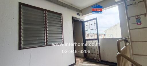 Outdoor hallway with a metal door and louvered window