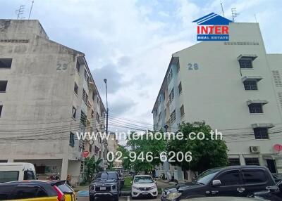 Two multi-story residential buildings with parked vehicles in front