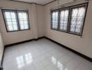 Empty bedroom with tiled floor and large windows