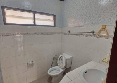 Bathroom with tiled walls, a toilet, sink, and frosted windows