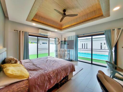 Modern bedroom with pool view and wooden ceiling
