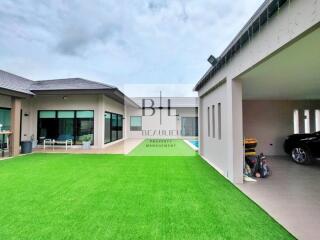 Modern property with green lawn, outdoor patio, and covered garage.
