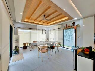 Modern dining area with wooden ceiling, large windows, and indoor plants