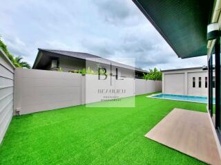 Backyard with green artificial grass and swimming pool