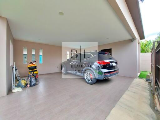 Covered garage space with car parked and some items stored