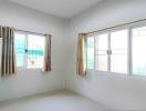 Bright bedroom with large windows and a green wardrobe