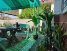 Outdoor patio with seating and plants under a shaded canopy