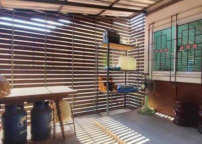 Covered outdoor patio with wooden slat walls and storage shelves