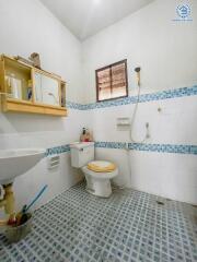 Bathroom with tiled floor and walls, single window, shower, sink, and toilet