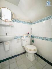 Bathroom with sink, mirror, toilet and tiled walls