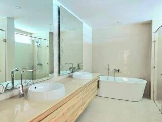 Modern bathroom with double sinks, bathtub, and shower