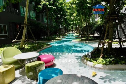 Outdoor seating area by a pool surrounded by greenery