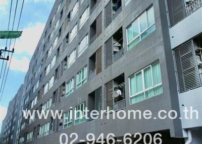 Exterior view of a multi-story residential building with parking area