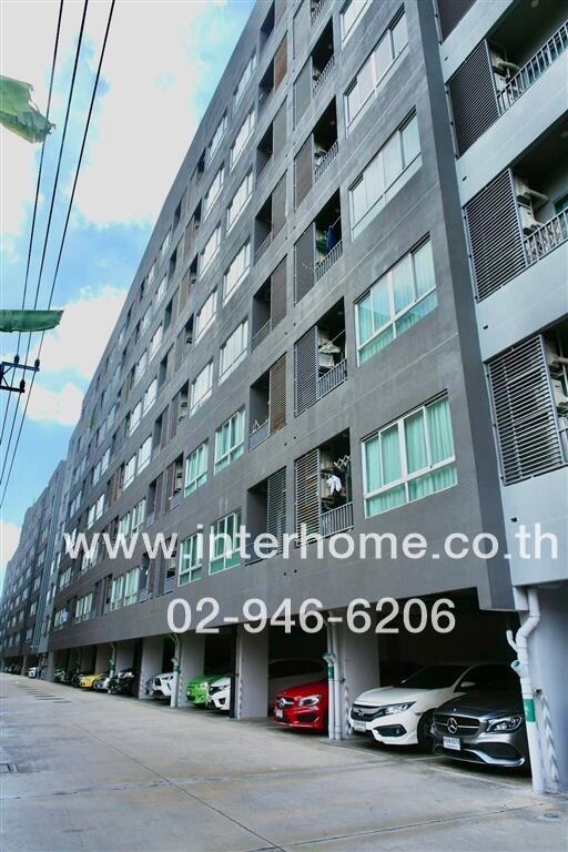 Exterior view of a multi-story residential building with parking area