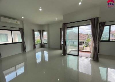 Spacious living room with large windows and tiled flooring