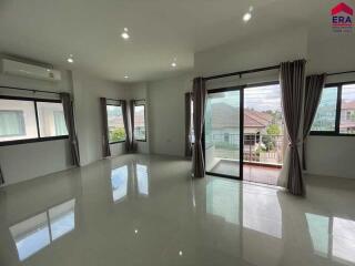 Spacious living room with large windows and tiled flooring