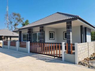 Exterior view of a modern single-story house with a fenced yard