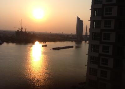 Sunset view from an apartment window overlooking water and cityscape