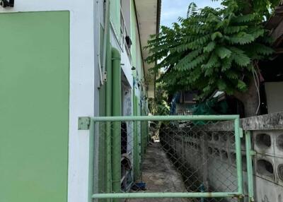 Exterior view with two-story green building and a fenced gate