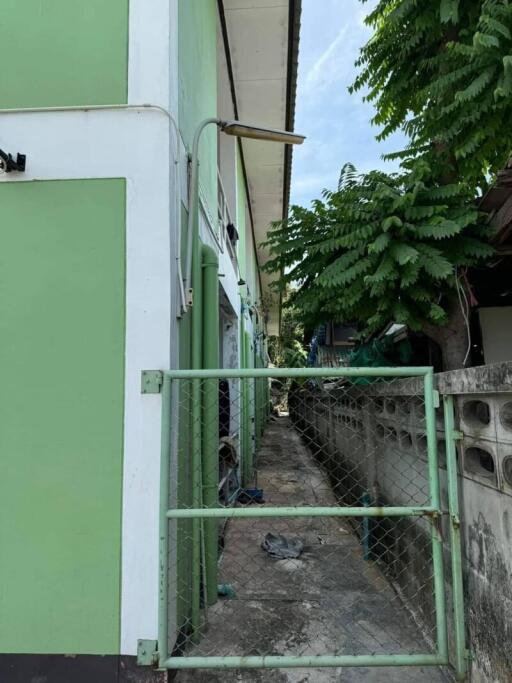 Exterior view with two-story green building and a fenced gate