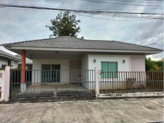 Front view of a single-story house with a tiled roof and a fenced yard.