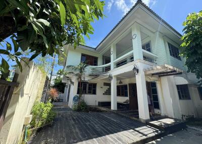 Exterior view of a two-story house with a large wooden deck and green paint