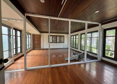 Spacious room with wooden floor, large windows, and glass partition.