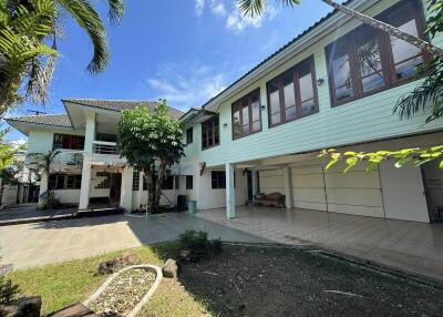 Exterior view of a two-story house with multiple windows, garage, and palm trees