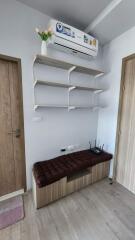 Utility room with shelves, a padded bench, and an air conditioner