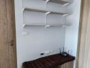 Utility room with shelves, a padded bench, and an air conditioner