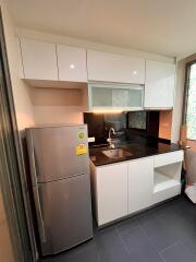 Modern kitchen with stainless steel refrigerator and black countertop