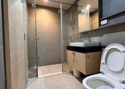 Modern bathroom with glass shower, toilet, and sink