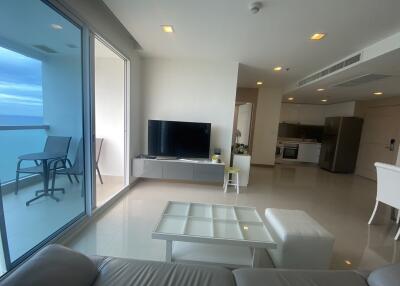 Modern living room with large glass doors, balcony view, and open kitchen