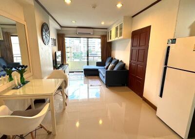 Modern living area with dining table, sofa, TV, and refrigerator