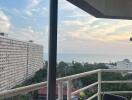 balcony with a view of the cityscape and ocean at sunset