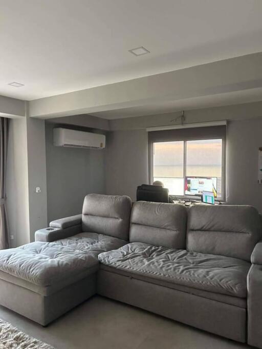 Modern living room with grey sectional sofa and air conditioner