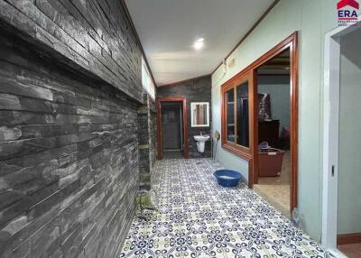 Hallway with stone wall, patterned floor tiles, and a view into a bathroom