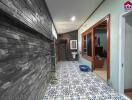 Hallway with stone wall, patterned floor tiles, and a view into a bathroom