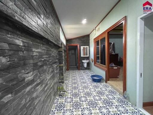 Hallway with stone wall, patterned floor tiles, and a view into a bathroom