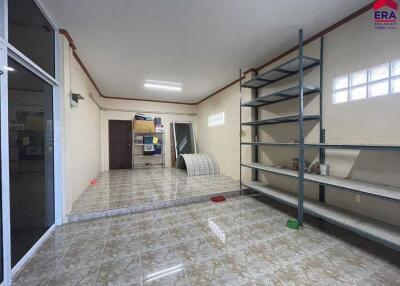 Spacious interior room with tiled flooring, shelvings, and partial furniture