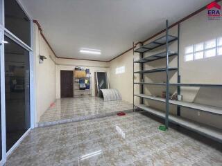 Spacious interior room with tiled flooring, shelvings, and partial furniture