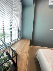 Bedroom with large window, wooden table, and flowers