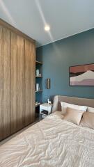 Modern bedroom with wooden wardrobe, blue accent wall, and double bed