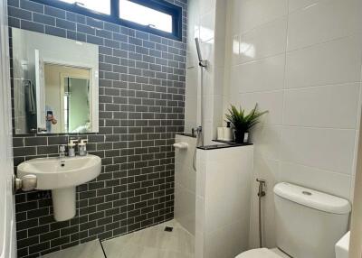 Modern bathroom with white fixtures and grey brick accent wall