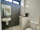 Modern bathroom with white fixtures and grey brick accent wall