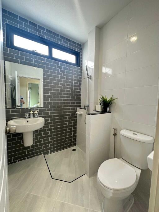 Modern bathroom with white fixtures and grey brick accent wall