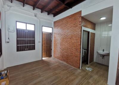 Interior view of a room with wooden ceiling, brick wall, and attached bathroom