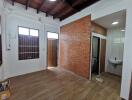 Interior view of a room with wooden ceiling, brick wall, and attached bathroom