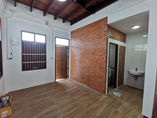 Interior view of a room with wooden ceiling, brick wall, and attached bathroom