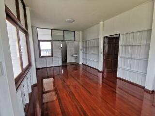 Living space with large windows, wooden floors, and built-in shelves.